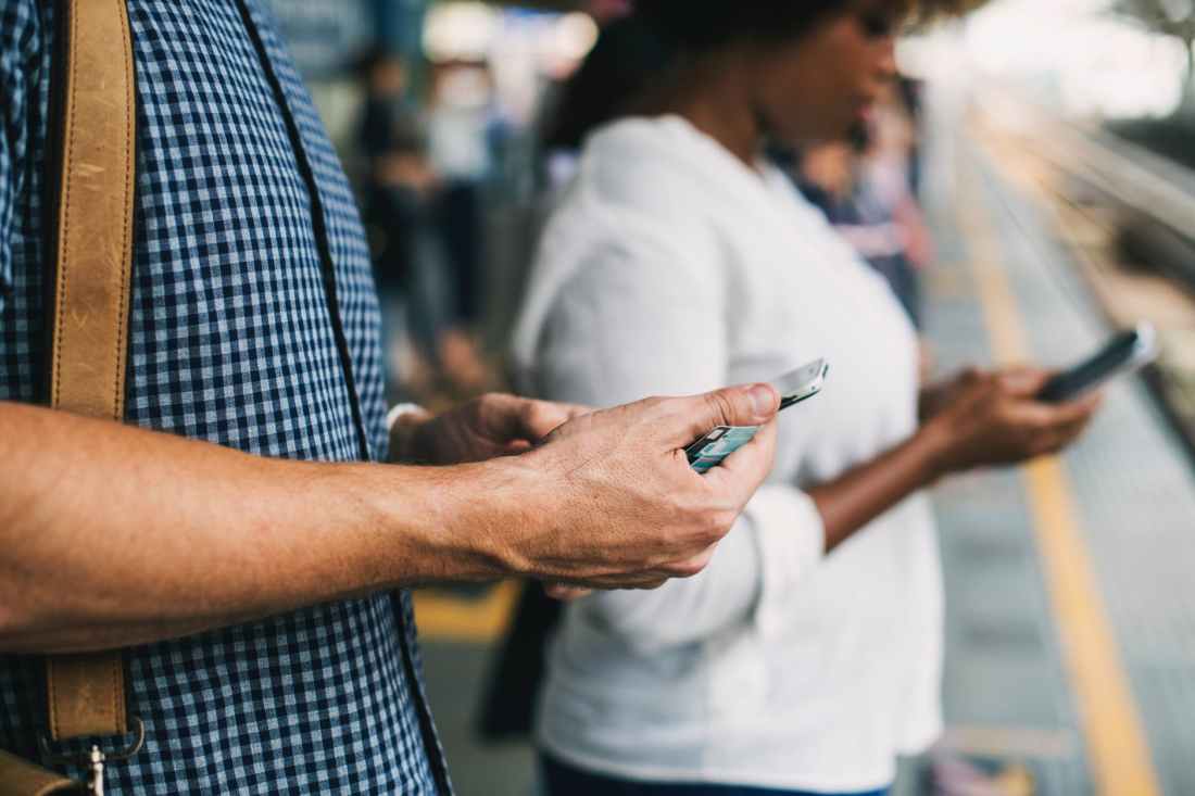 person holding cellphone while standing on train station